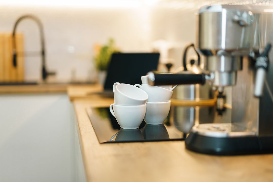 A home espresso machine with cups on a kitchen counter.