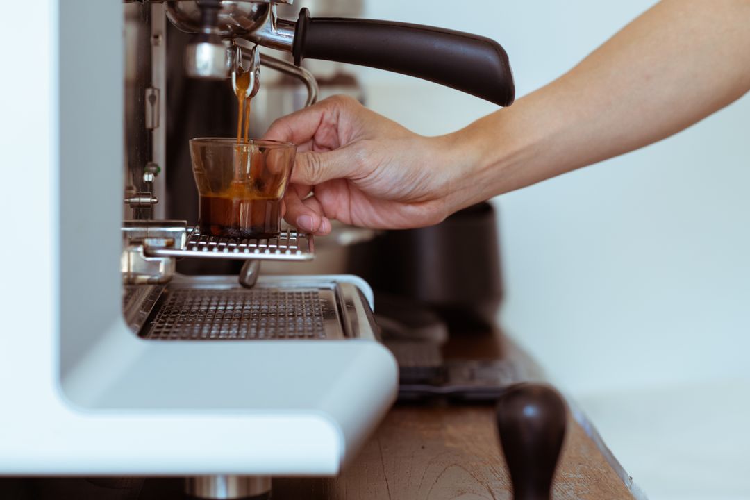A double espresso extracting from a bottomless portafilter into a glass.